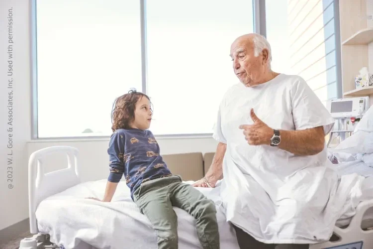Image of older patient on hospital bed talking with a young child