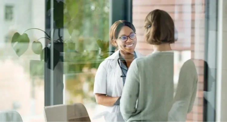 Two women talking in an office with green plants