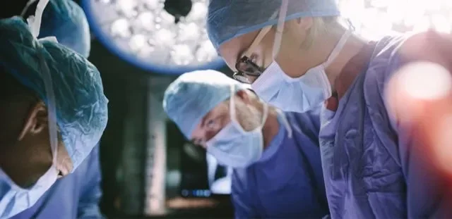 Surgeons viewing a patient under a bright surgical light.