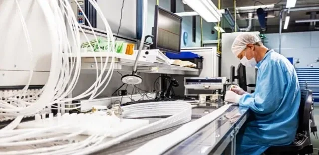 A healthcare professional in surgical PPE viewing a medical equipment.