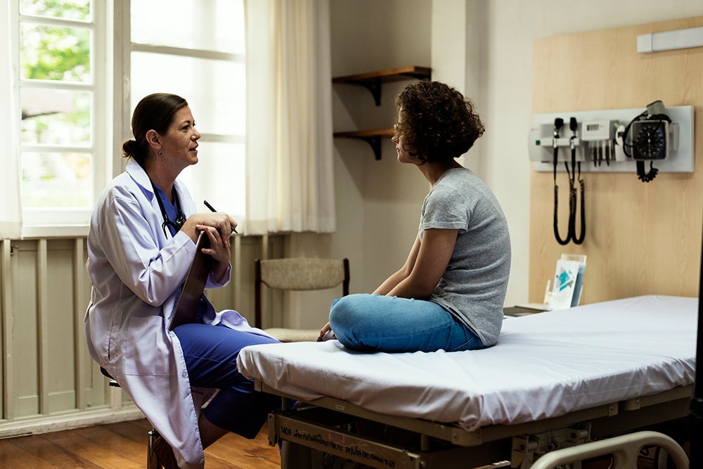 Doctor speaking with a patient seated on an exam table