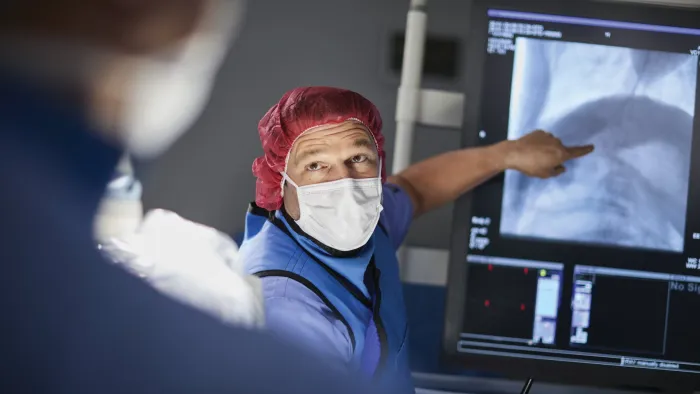 male physician in operating room pointing to an x ray
