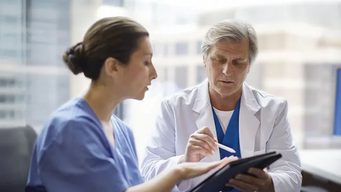 Healthcare professionals reviewing a tablet device.