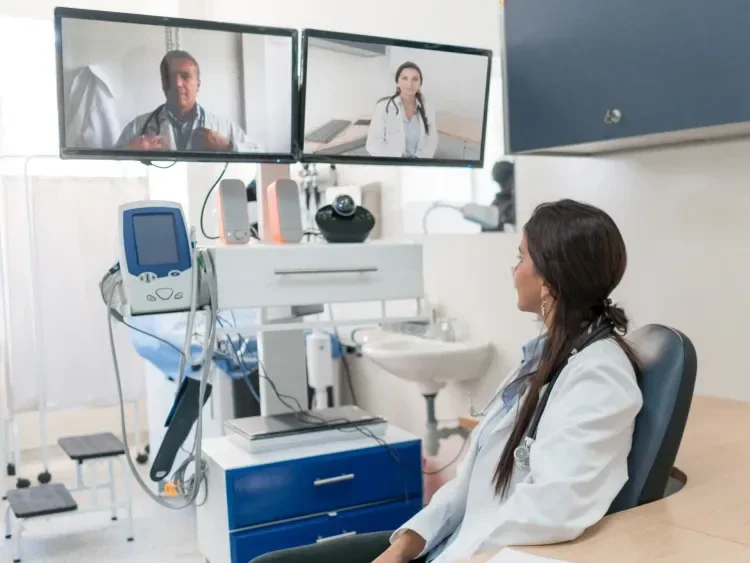 Doctor meeting virtually with other doctors on computer screens