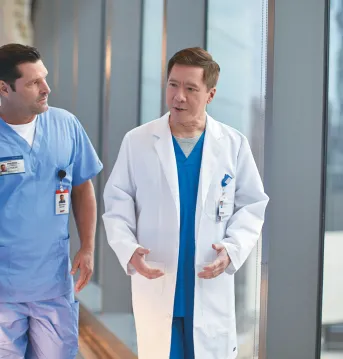 two male physicians walking down a hall talking to each other