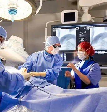 physicians wearing blue scrubs in an operating room in discussing the case