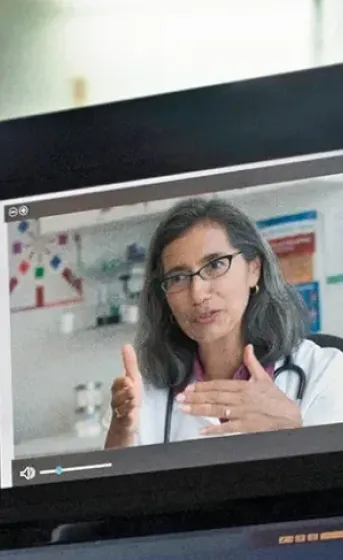 male physician on a video conference call looking at three other physicians on various screens